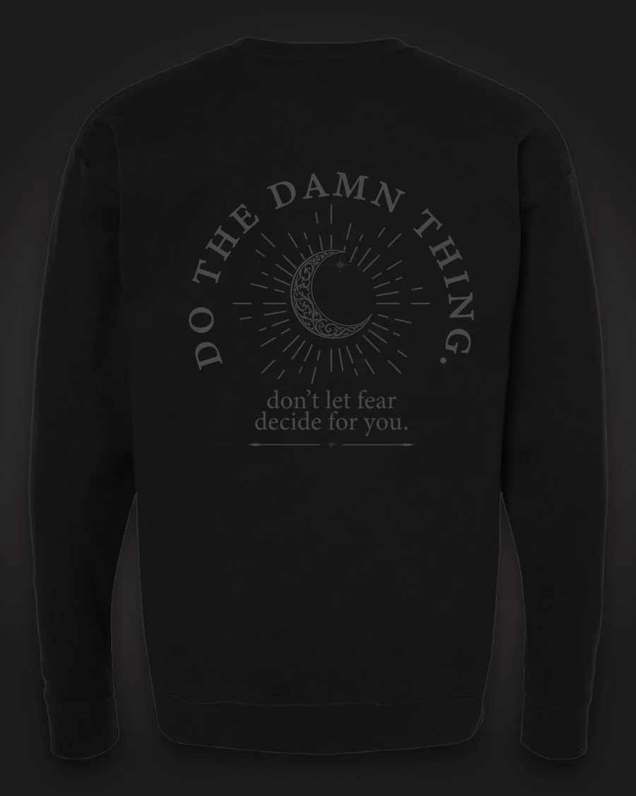 Mockup, back: black crewneck with a crescent moon in a sunburst, ringed by the words “Do the damn thing.” with “don’t let fear decide for you.” beneath.
