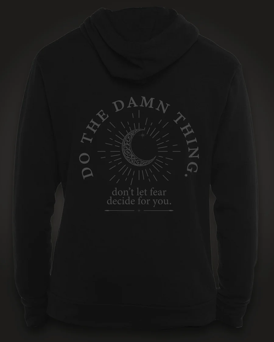 Mockup, back: black hoodie with a crescent moon in a sunburst, ringed by the words “Do the damn thing.” with “don’t let fear decide for you.” beneath.