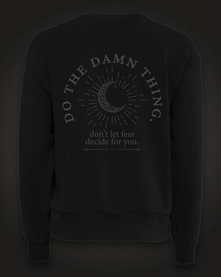 Mockup, back: black women’s crewneck with a crescent moon in a sunburst, ringed by the words “Do the damn thing.” with “don’t let fear decide for you.” beneath.