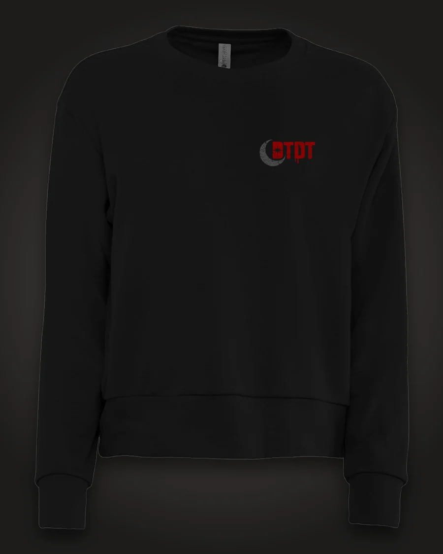 Mockup, front: black women’s crewneck with the DTDT crescent mark in grey and dripping red on the left chest.